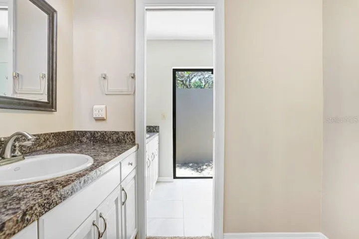 Primary Bathroom with view of 2 vanities and exit to pool area