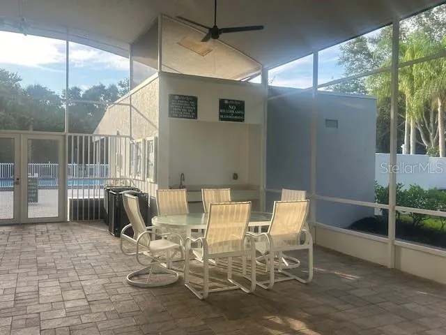 Screened-in entrance to community pool and locker rooms with multiple tables and chairs.