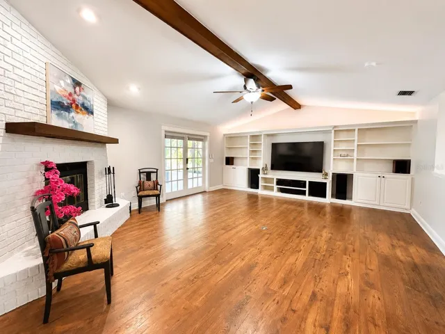 A stylish living room made to glow, with a cozy white brick fireplace, and a custom entertainment wall featuring color-changing lights for the perfect movie-night mood.