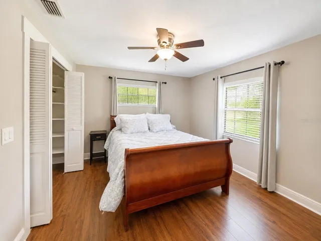 Bright secondary bedroom with warm wood-like floors, great natural light, and a spacious closet for extra storage.