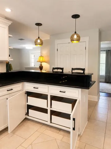 Chic kitchen details shine with warm pendant lighting, a convenient breakfast bar, and pull-out lower cabinets that make storage both stylish and functional.