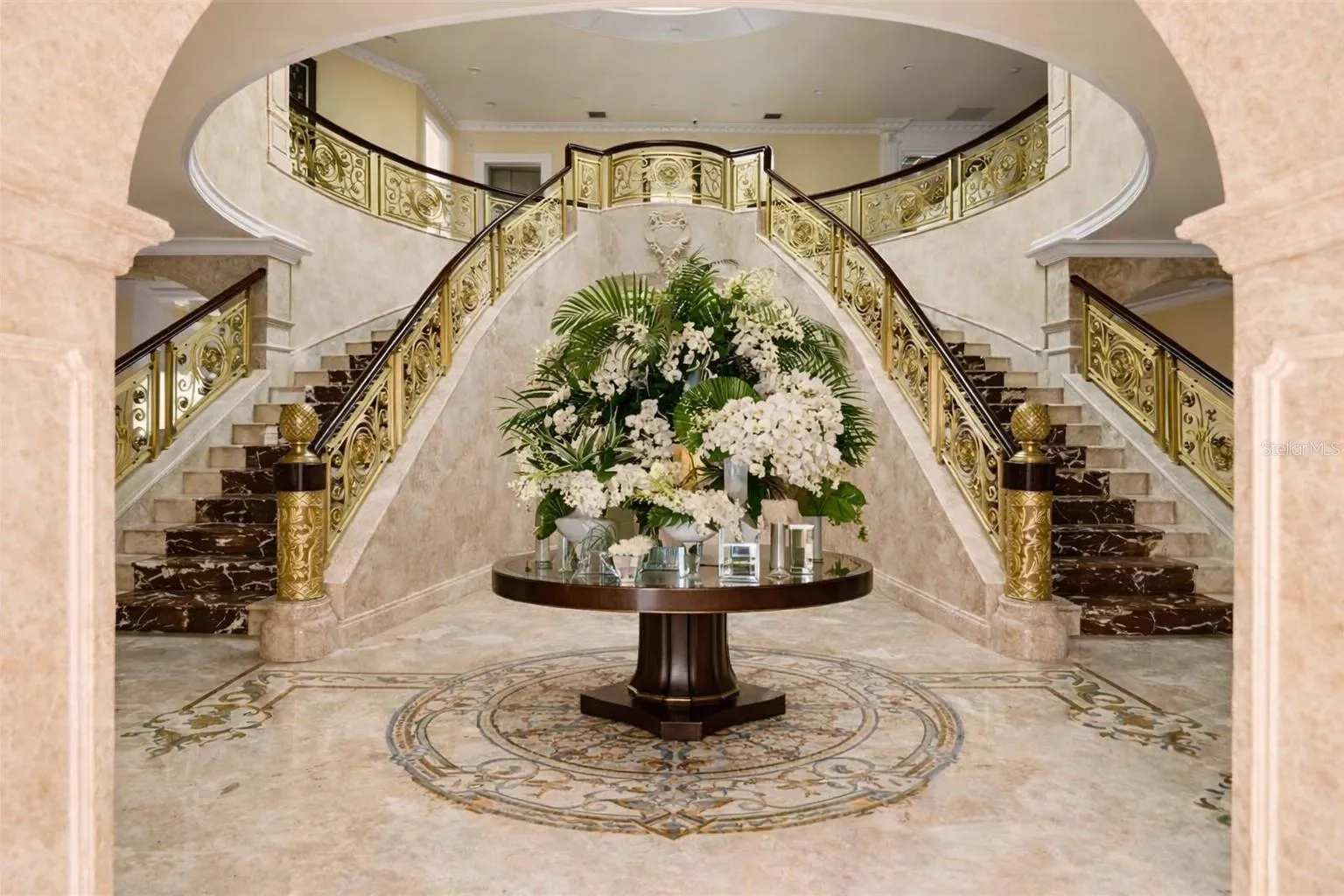 Dramatic rotunda with statement chandelier and marble staircases.