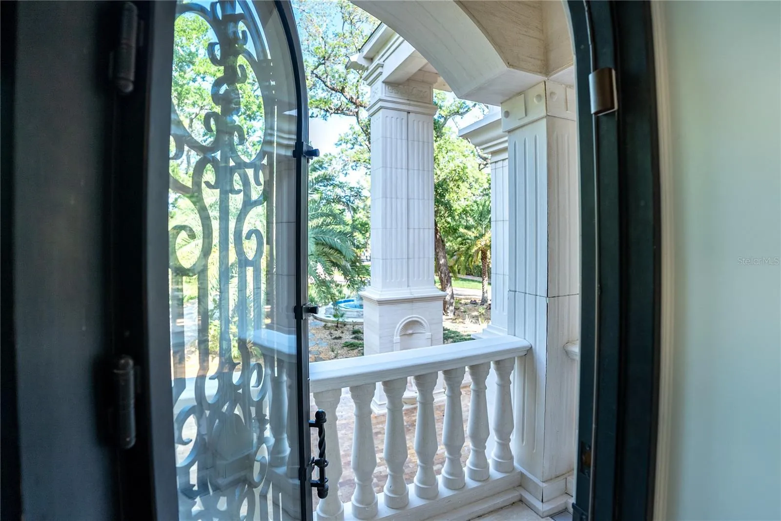 Arched black iron doors open to a private lanai off the spa-inspired marble bath with sauna, soaking tub, and custom detailing.