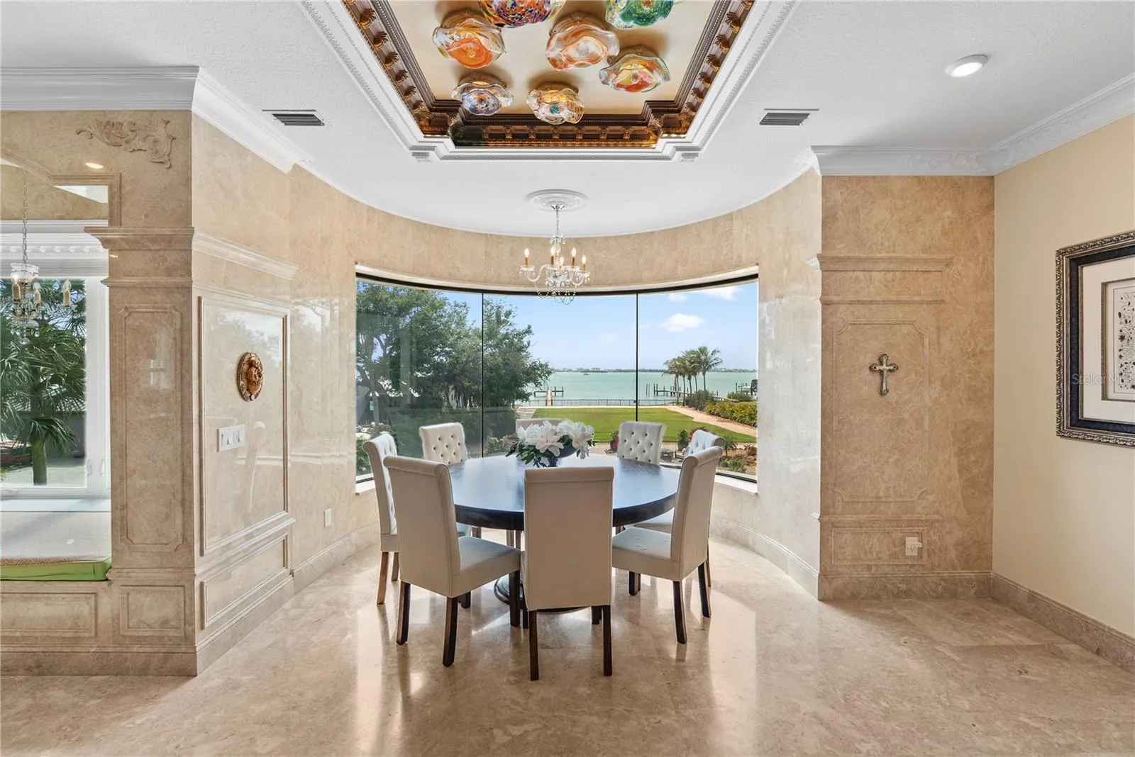 Curved glass dining area with panoramic water and pool views.