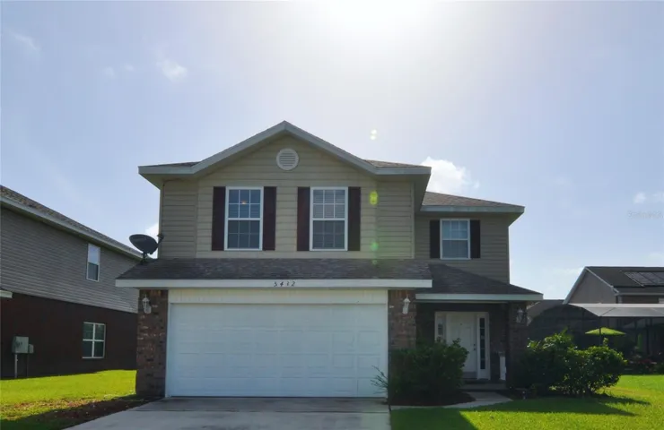 A charming two-story home with a welcoming façade, featuring a combination of brick accents and siding, a spacious two-car garage, and a well-maintained lawn.