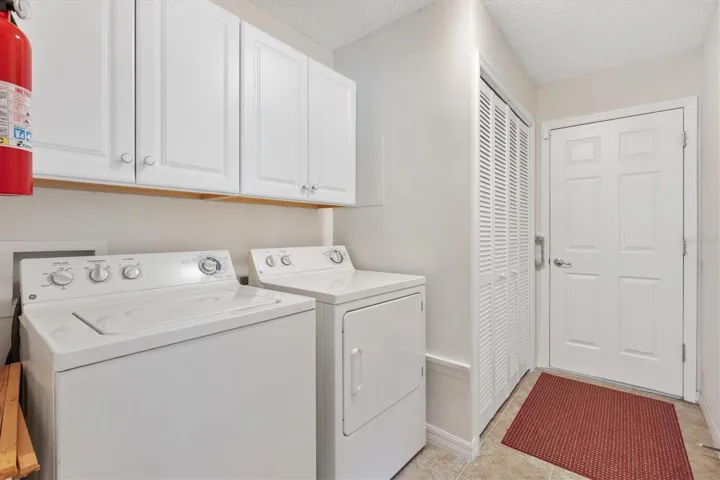 Inside laundry room with washer, dryer and cabinets for storage.  2 car garage through door.