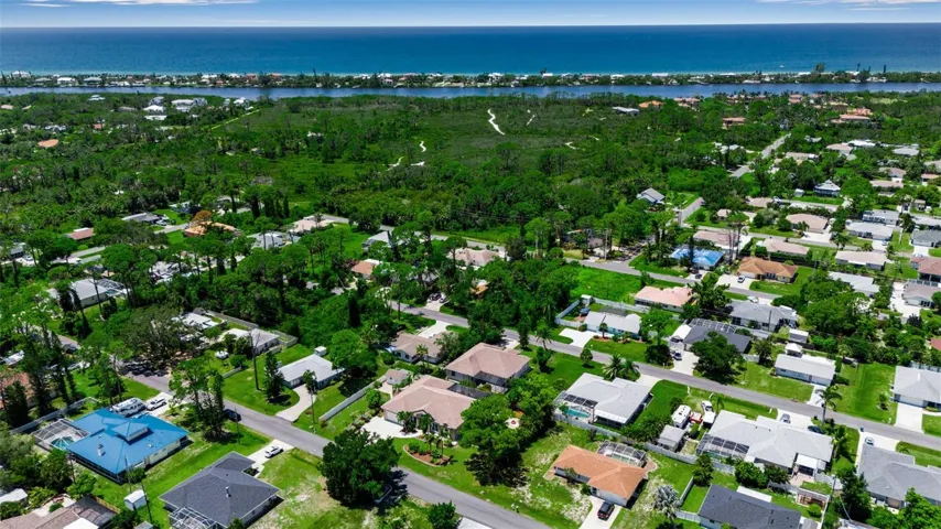 Aerial view of the home and surrounding neighborhood with lush landscaping and convenient access to nearby amenities