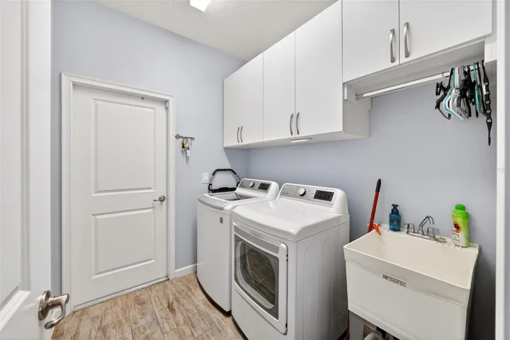 Laundry room with custom cabinets and utility sink and door to garage