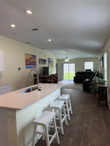 Interior kitchen island with sink looking into great room, vaulted ceiling.