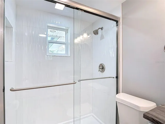 Wavy Tile shower stall with brushed nickel fixtures! Plenty of Light Too!