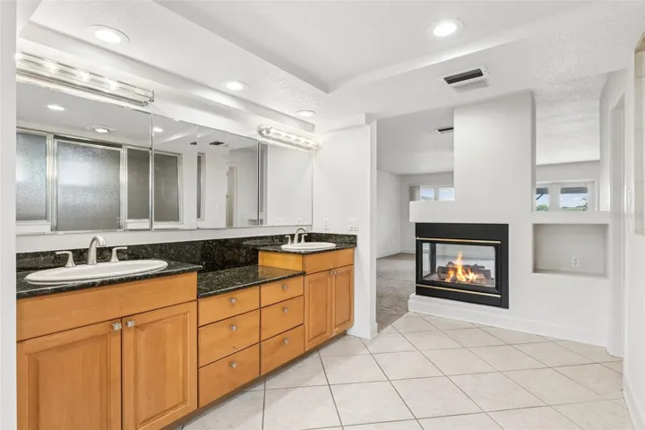 Primary bathroom with dual vanities and a two-sided fireplace shared with the master bedroom.