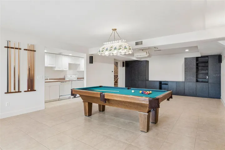Full-size basement living room with kitchenette, offering separate living quarters with a bedroom and full bath leading to the pool deck.