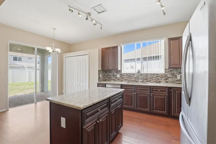 Open Kitchen with Granite Countertops, Center Island, Tile Backsplash, and Stainless Steel Appliances