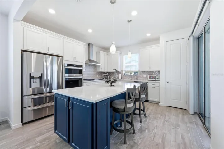 Chef Kitchen with top tier two tone cabinets and thickest level of Quartz. Cabinets on end of island; stainless steel hood