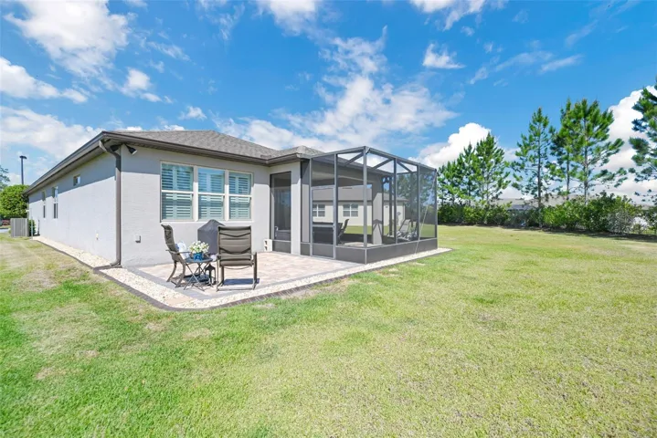 View of Rear of Home w/ Extended Screened Lanai + Cage + Open Paver Patio on Expansive Pie-Shaped Lot