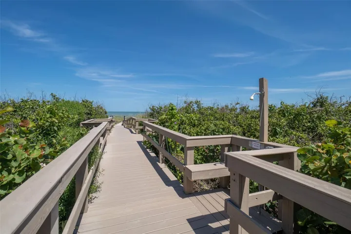 Beach access boardwalk at Windward East with outdoor rinse shower and native dune vegetation — direct Atlantic Ocean access