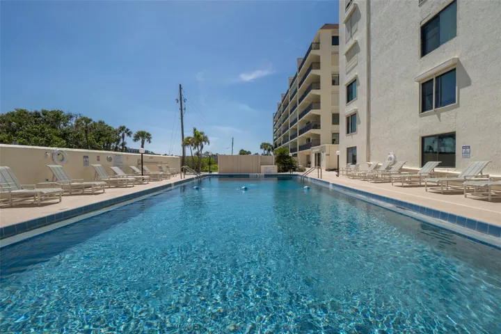 Large, heated community swimming pool at Windward East in Cocoa Beach with lounge chairs and poolside seating