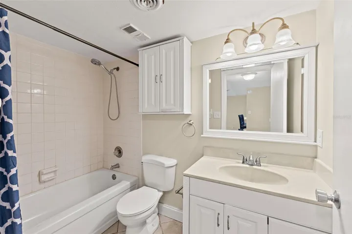 Full bathroom with tub/shower combo, white vanity, single sink, and linen storage