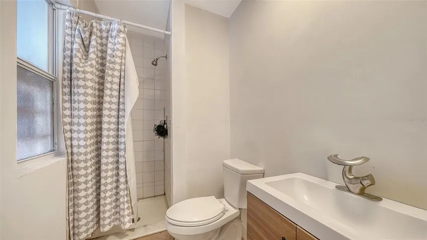 Apt #2 bathroom with tiled shower, sink cabinet and toilet