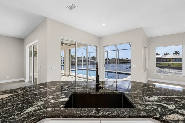 Kitchen with granite countertops, a water view, and recessed lighting