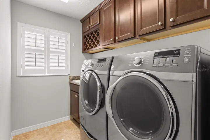 laundry room features jumbo washer/dryer, sink, cabinetry, and built-in wine storage.