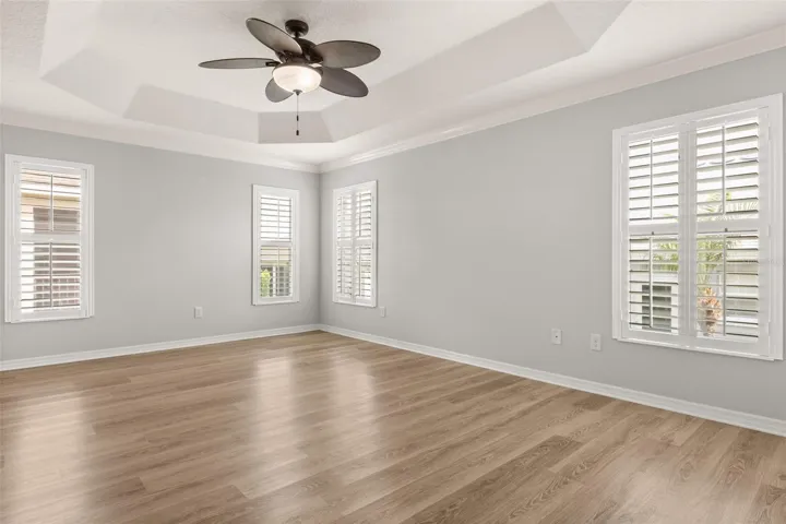 Spacious primary suit with tray ceiling, ceiling fan, plantation shutters, pocket door to primary bath.