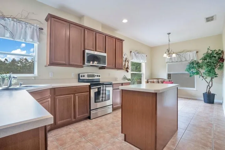 The spacious Kitchen is designed for both everyday living and entertaining, featuring stainless steel appliances, a CENTER ISLAND, breakfast bar, closet pantry, and abundant cabinetry and counter space, along with a SUNLIT BREAKFAST NOOK perfect for casual mornings.