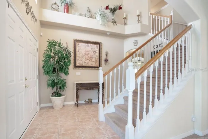 Step through the double-door entry into a dramatic foyer with SOARING CEILINGS and a sweeping staircase, creating an immediate sense of space and sophistication.