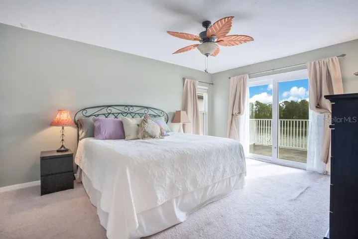 Upstairs, the Primary Suite feels like a private escape, featuring a stylish ceiling fan, DUAL WALK-IN CLOSETS, and PRIVATE BALCONY ACCESS through sliding doors, where you can unwind while taking in peaceful water views.