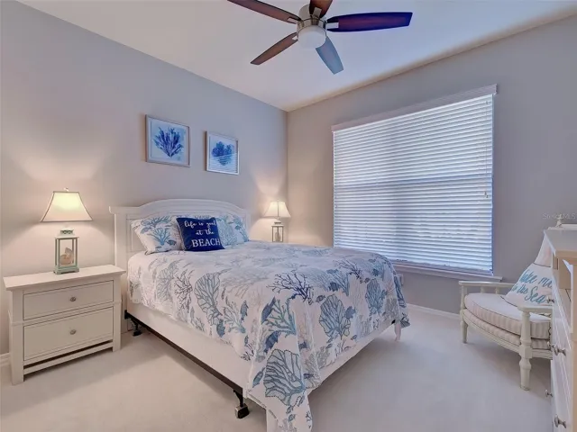 Guest bedroom with new carpet, double window and ceiling fan.