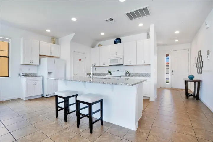 Bright kitchen with white cabinets and breakfast bar seating.
