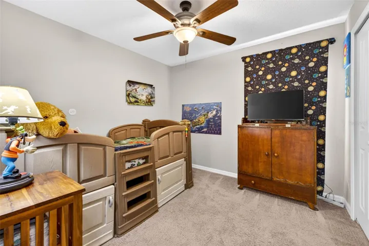 Secondary bedroom with ceiing fan and built in closet