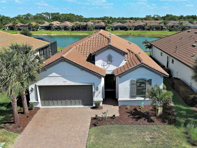 Gorgeous Florida-style home with a tile roof, driveway pavers on a pond.