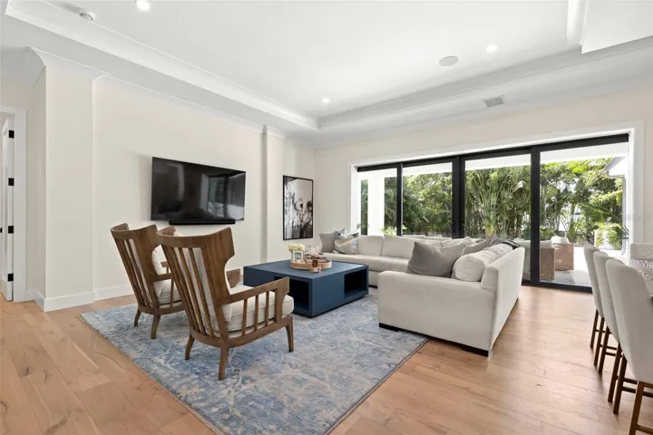 Light-filled living room featuring elegant tray ceilings and expansive sliding glass doors that open to a private outdoor retreat