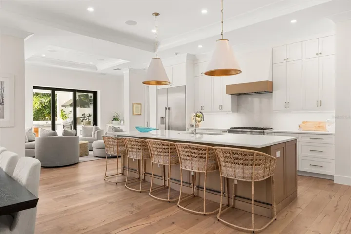 Stunning chef’s kitchen featuring an oversized island with seating, custom cabinetry, sleek quartz countertops, designer pendant lighting and top-of-the-line Thermador appliances
