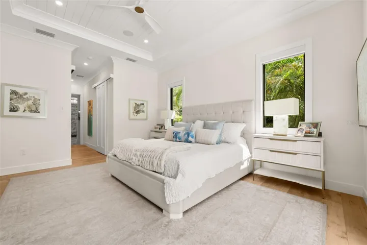 Serene primary suite featuring a vaulted tray ceiling with wood detailing, and tranquil views of lush tropical landscaping