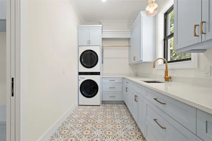 Well-appointed laundry room featuring custom cabinetry, and a convenient utility sink with designer fixtures.