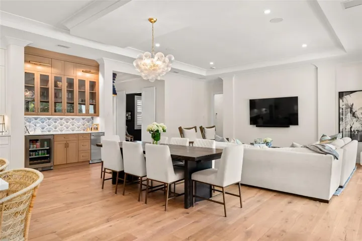 Custom dry bar featuring glass-front cabinetry, designer tile backsplash, beverage refrigerator, and additional storage—perfect for entertaining with style and convenience