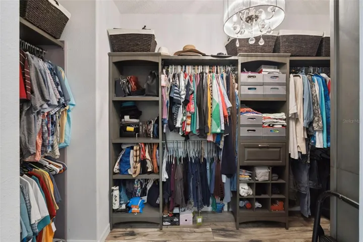 A spacious walk-in closet with a custom organizer system and an elegant chandelier