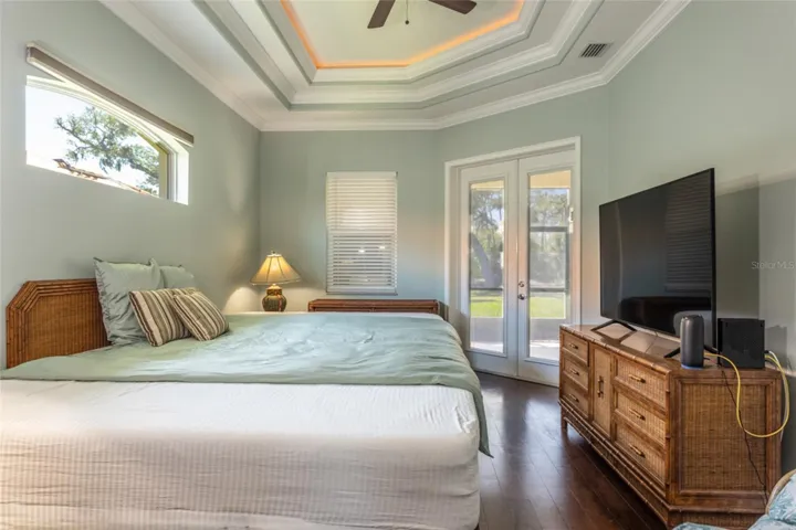Primary bedroom with multi-tiered tray ceilings & french doors leading to back lanai