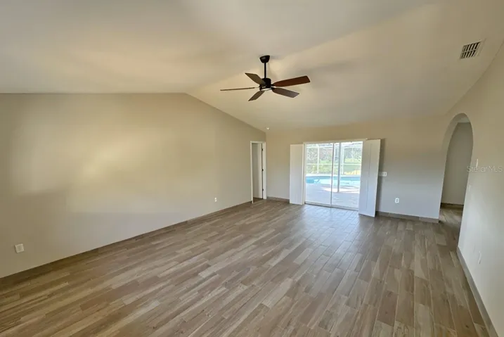 living room with sliders to pool area - archway to right leads to dining and kitchen