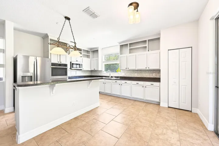 The UPDATED KITCHEN is the heart of the home, complete with BUILT-IN DOUBLE OVENS, stainless steel appliances, a neutral color palette, abundant cabinetry, pantry storage, and a large ISLAND with bar seating.
