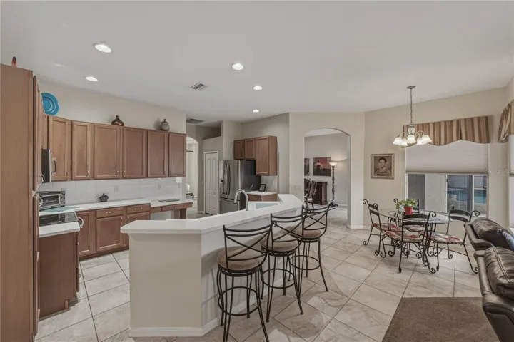 Bright, open-concept kitchen flowing into a cozy breakfast nook and spacious family room, perfect for everyday living and entertaining with direct access to the pool.