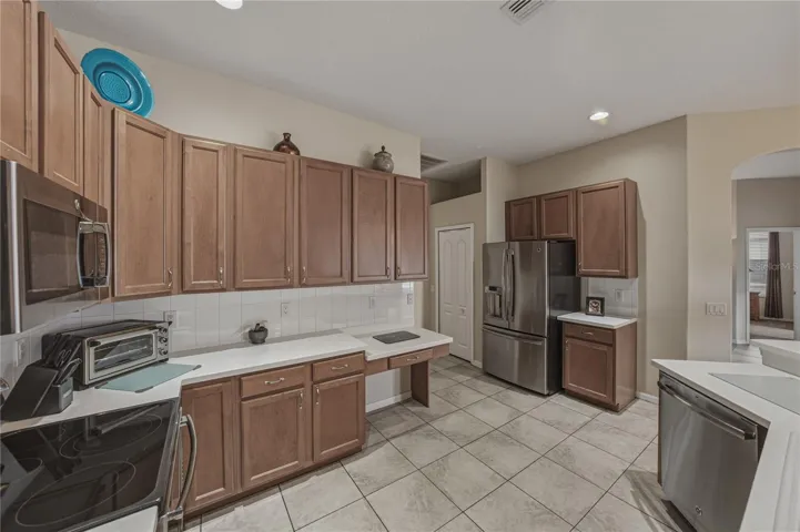 Bright, open-concept kitchen flowing into a cozy breakfast nook and spacious family room, perfect for everyday living and entertaining with direct access to the pool.