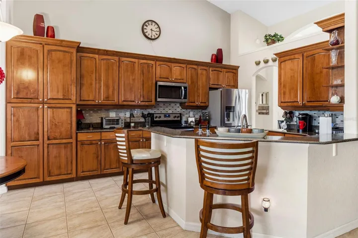 Kitchen offers solid wood cabinetry, cabinet pantry, stainless steel appliances, backsplash and breakfast bar