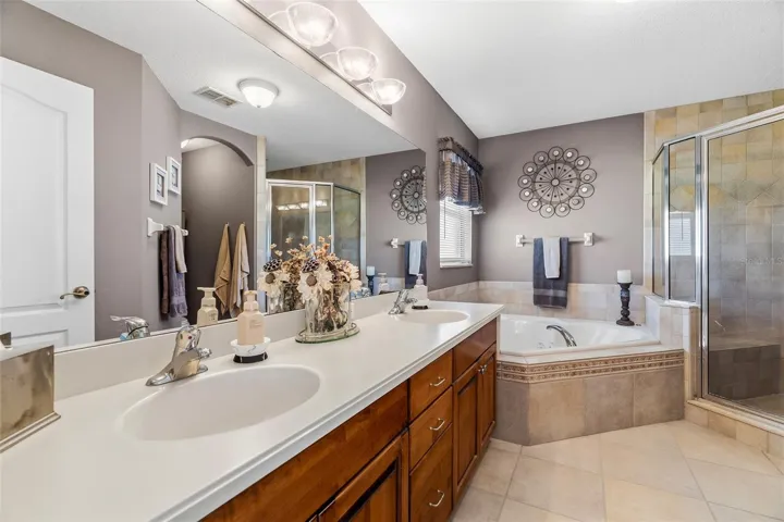 Primary ensuite bathroom featuring dual sinks and stone top vanity top