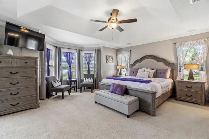 Oversize primary bedroom features tray ceiling and 2 closets, one being a walk-in