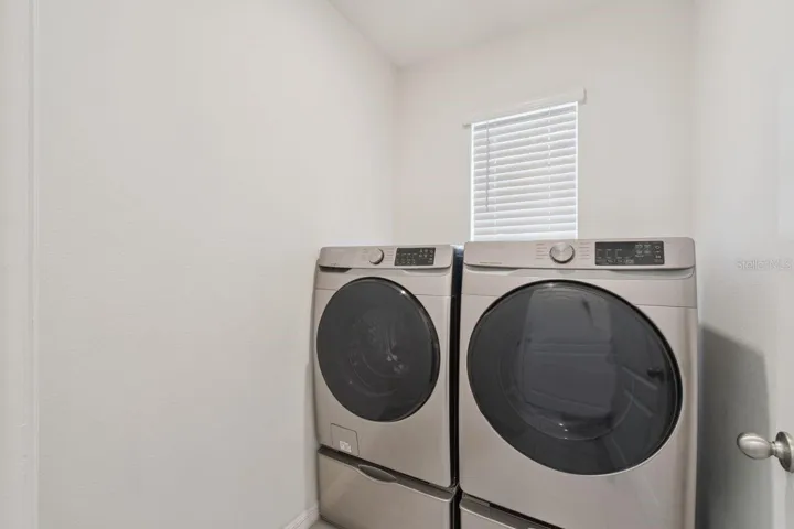 Inside laundry room with large capacity washer & dryer included.