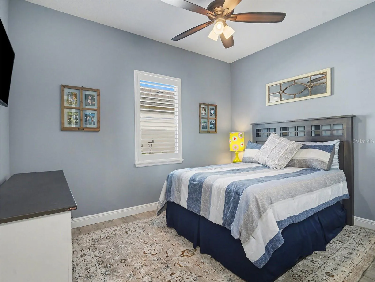 Bright guest bedroom with ceiling fan, soft natural light, and a comfortable layout for family or overnight visitors.
