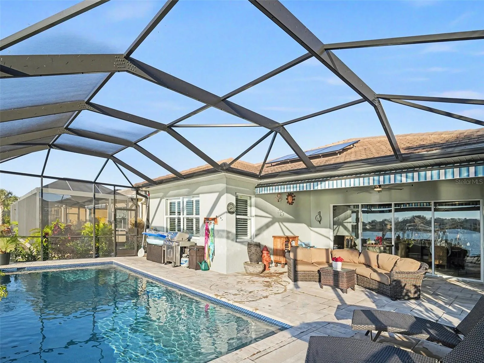 Resort style pool area under screen enclosure with generous deck space for lounging, dining, and enjoying the waterfront backdrop.